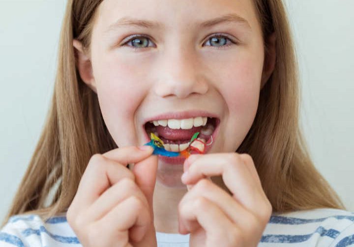 Dental plate. Expansion of the jaw in a child. A plate to heaven. There is not enough room for the molars. Happy girl holding an orthodontic plate in her hands